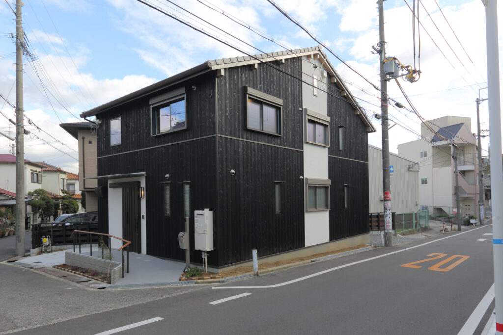 竣工した大切妻屋根の家の外観、焼杉と漆喰の外壁