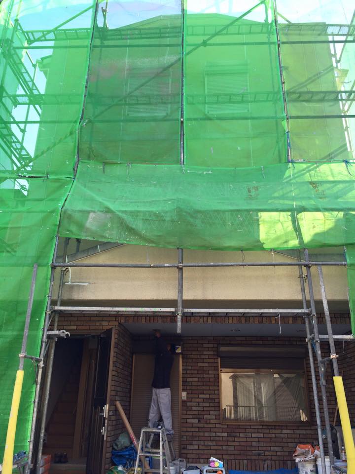 外壁改修工事中・建物全体に足場を組んで緑のネットで養生した状態