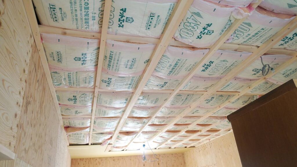 屋根裏に断熱材を敷き込んでいる施工の様子