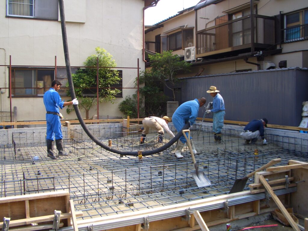 基礎のベースコンクリートを打設している職人