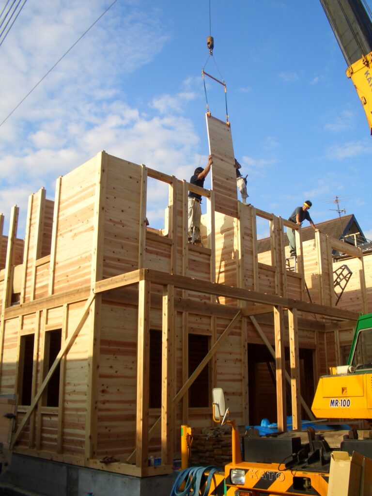 クレーンで板倉のパネルを落とし込んでいく様子