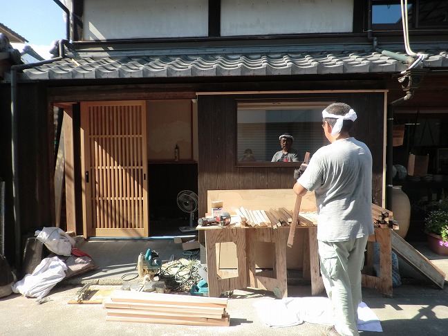 玄関廻りの施工作業中、職人が焼杉の仕上げを行っている