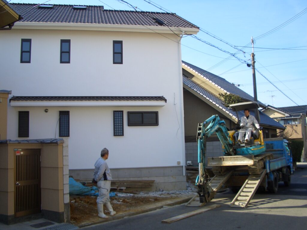 外構工事中の漆喰外壁の家の外観。敷地に対して斜めに配置されている