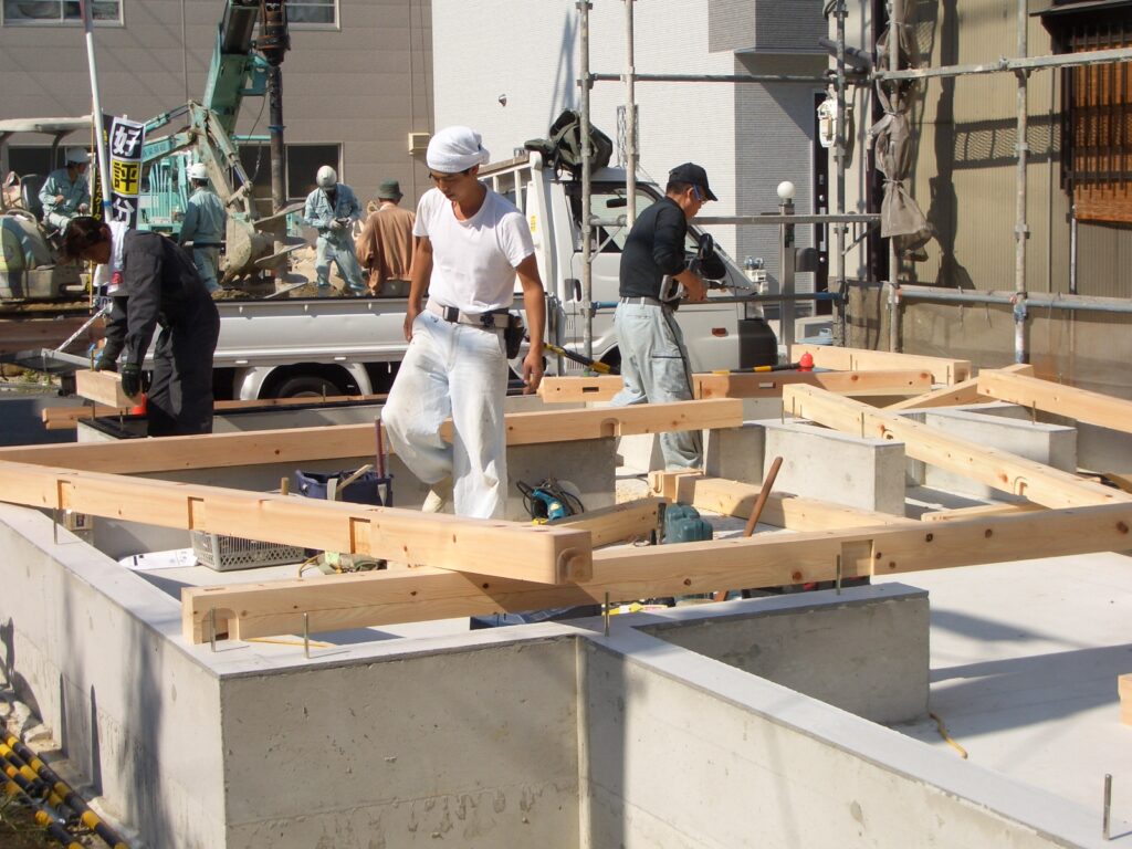 大工が基礎の上に土台を敷いている作業の様子