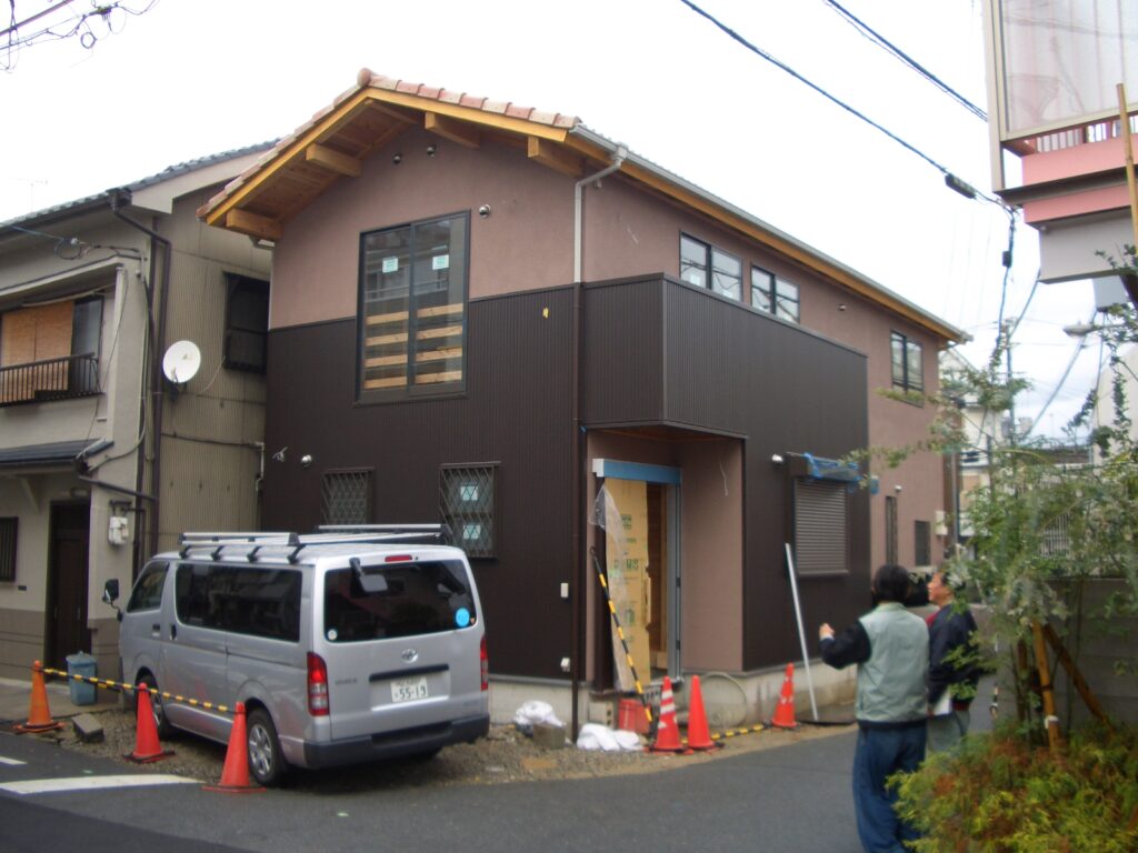 足場が外れて外観が現れた板倉造りの家。こげ茶のガルバリウム外壁