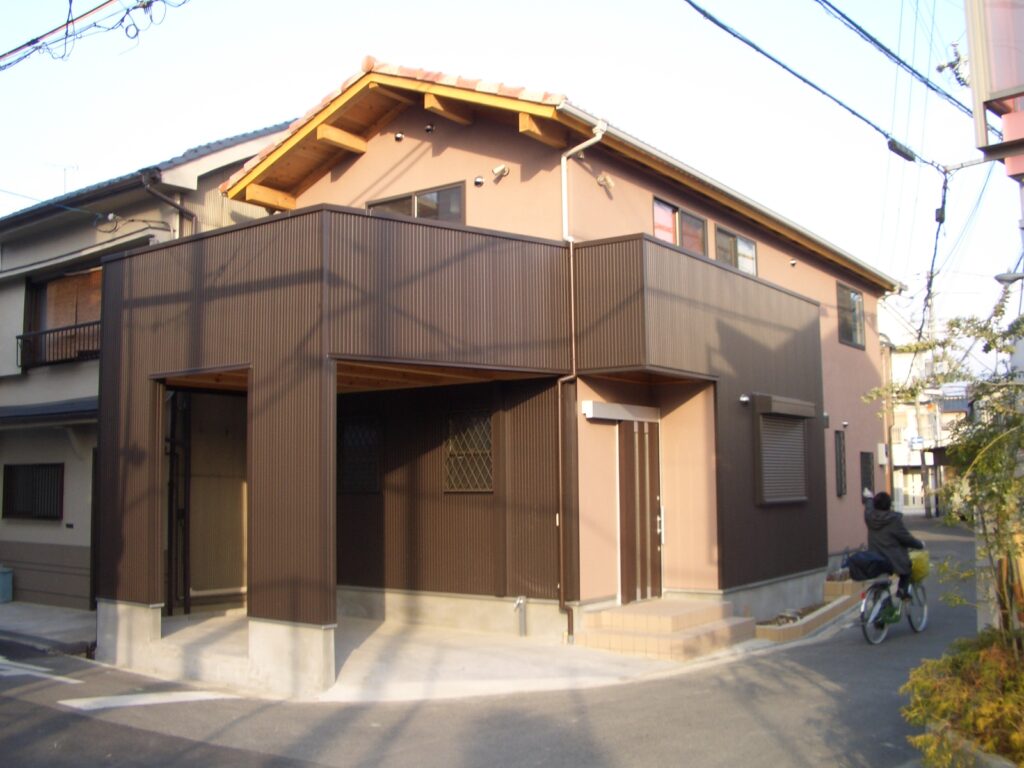 完成した板倉造りの家の外観。こげ茶のガルバリウム外壁にガレージ付き