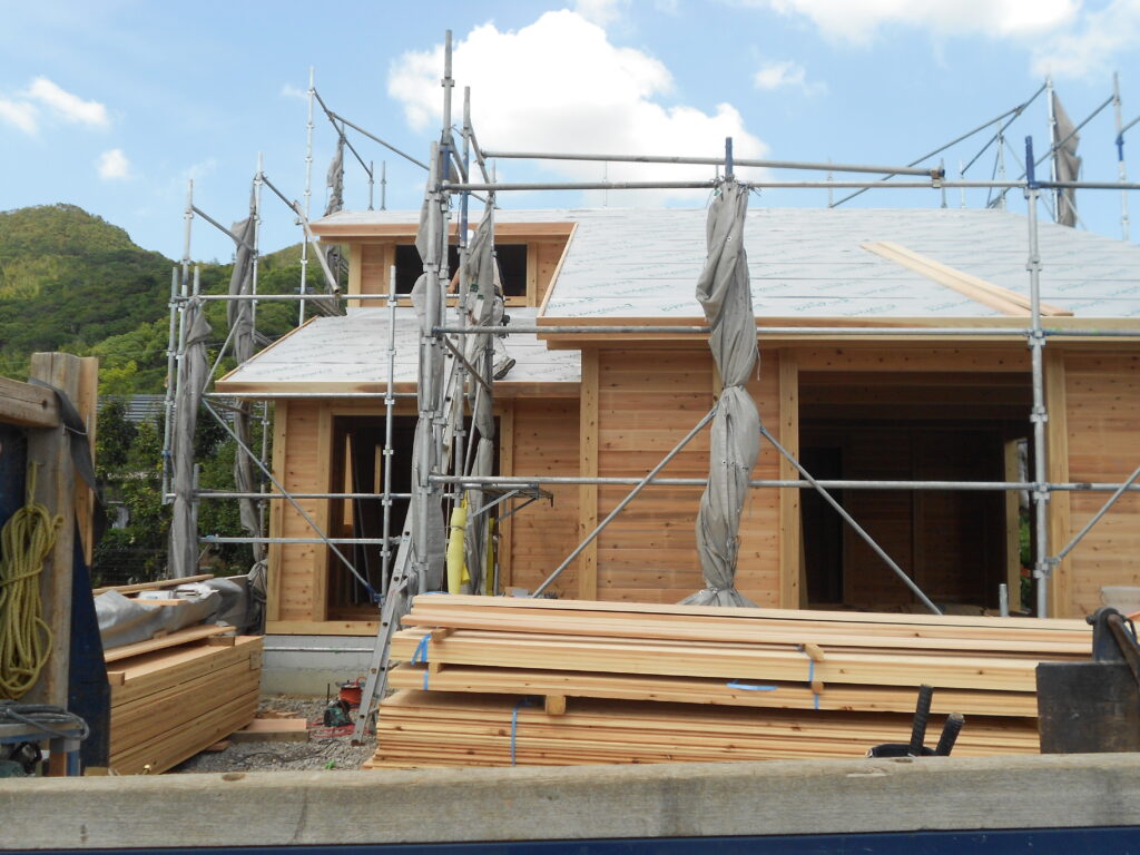 屋根廻りの工事が進む板倉造りの家の外観