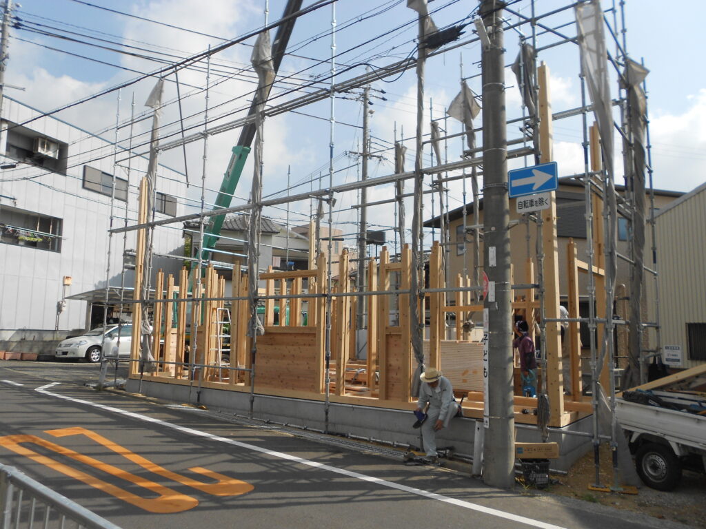 板倉造りの建て方の様子、クレーンで木材を吊り上げている