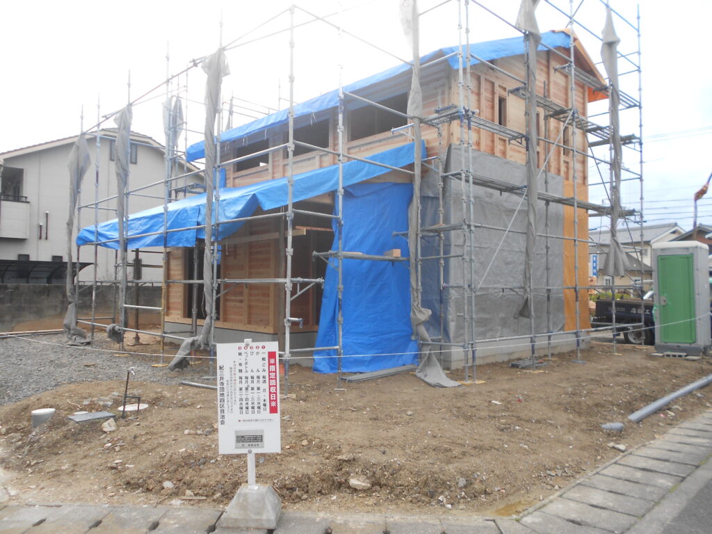 建て方が進み足場に覆われた板倉造りの建物外観