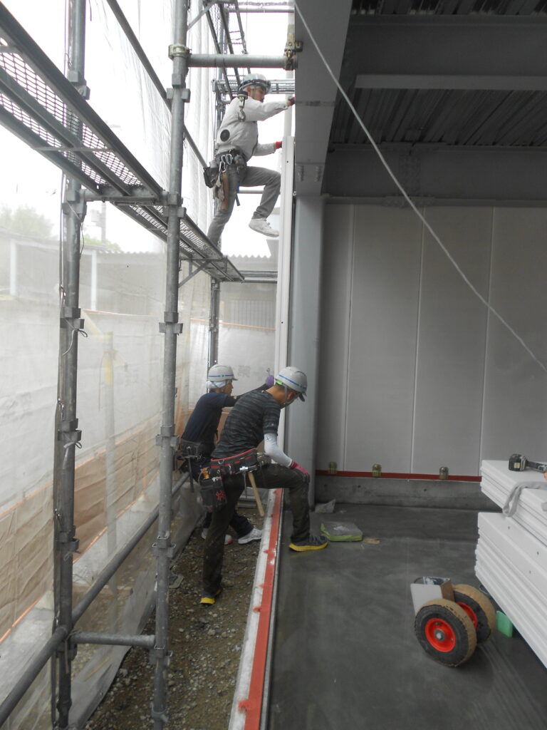 外壁ALC板を職人が足場上で施工している様子