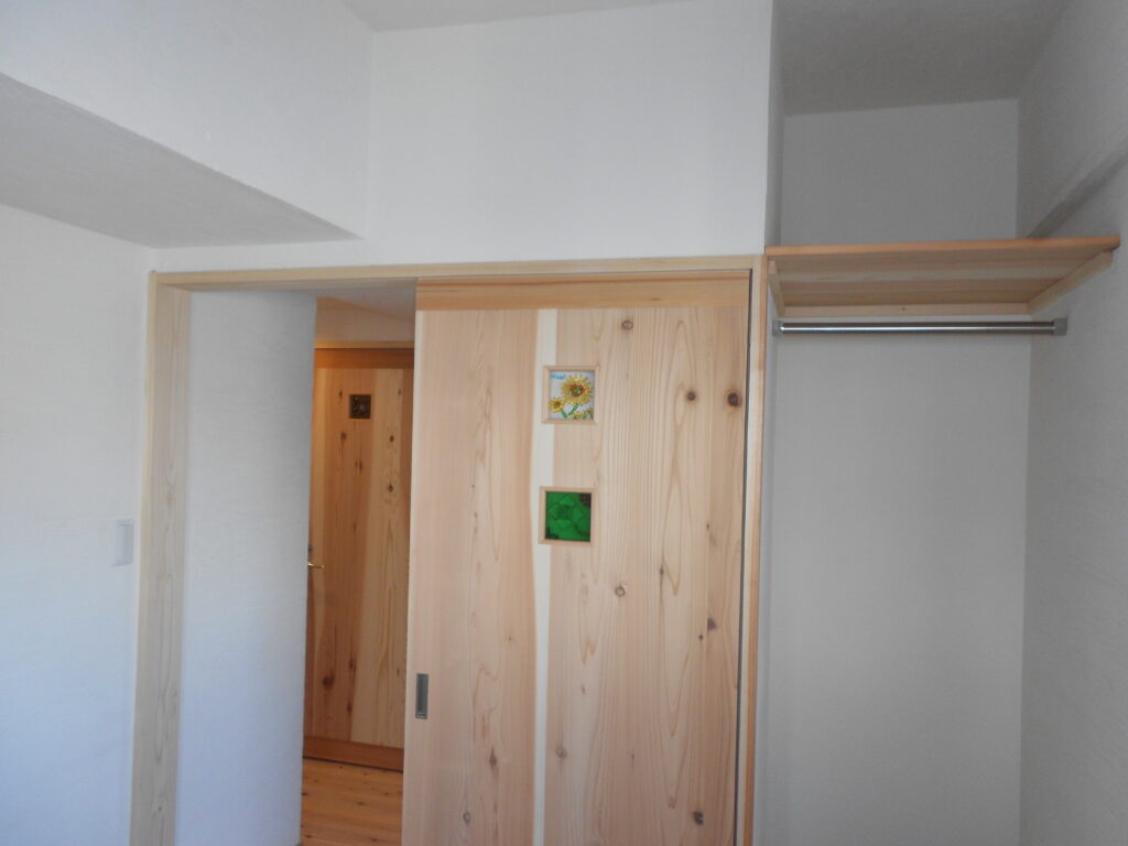 漆喰壁と調和する無垢材の引き戸が取り付けられた室内