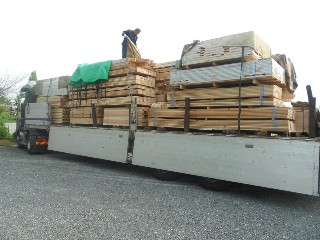 板倉造りの庫裏に搬入された大量の木材を積んだトレーラー