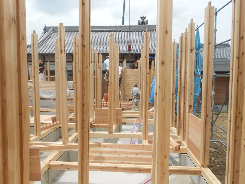 板倉造り庫裏の建て方1階、柱を建て杉板を落とし込んでいる様子
