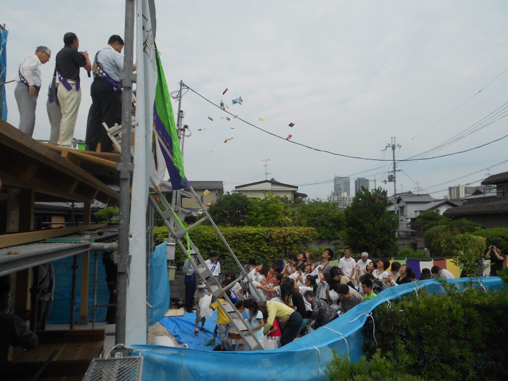 お寺の庫裏の上棟式でお餅撒きが行われている様子