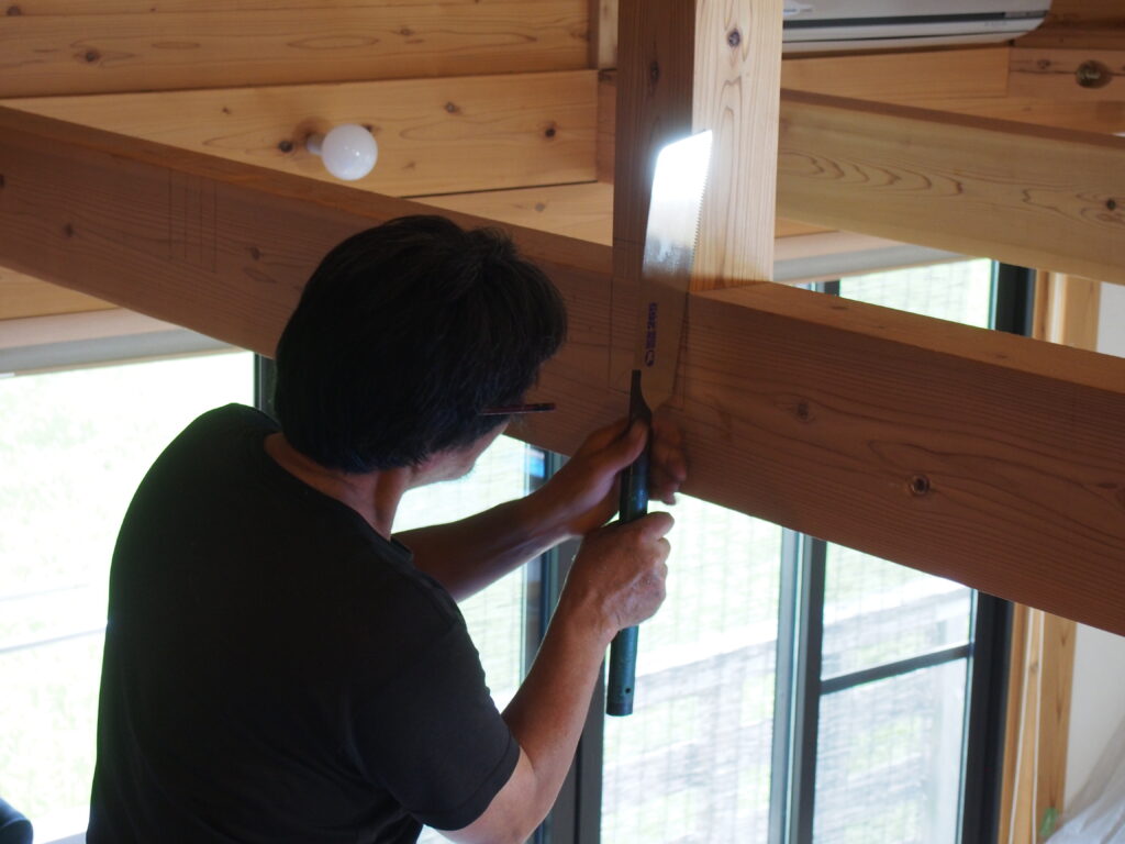 大工が既存の梁に小梁を取り付けるため仕口を刻んでいる様子