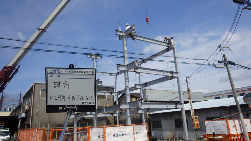 レッカー車で鉄骨を吊り上げて建て方を行う様子