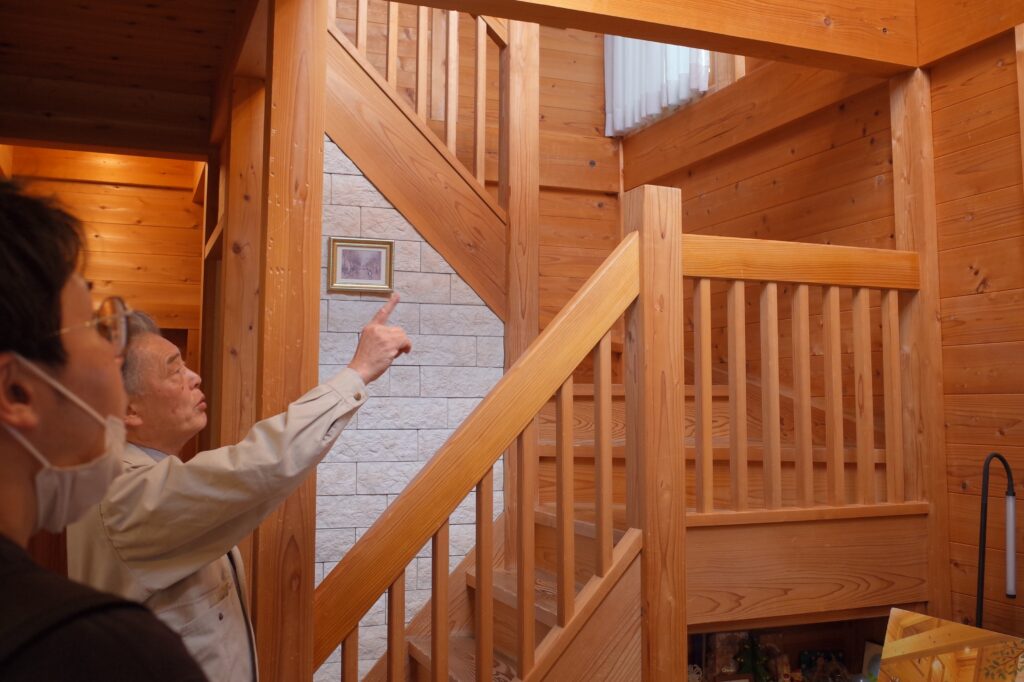 経年変化で表面があめ色に変わってきた気の家をお客様にご紹介しているところ。