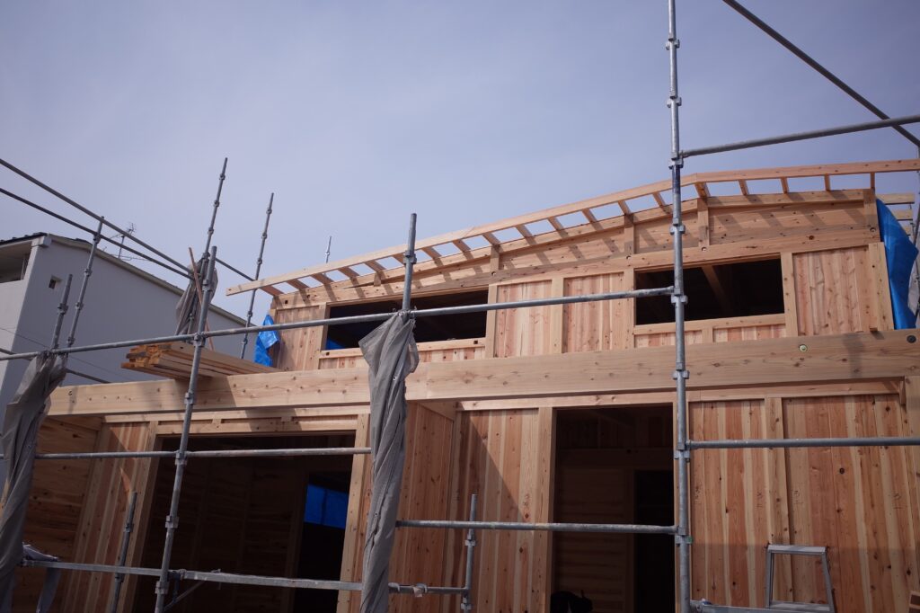 建築中の板倉造りの住宅の正面。柱の間に落とし込んだ板が見えている。