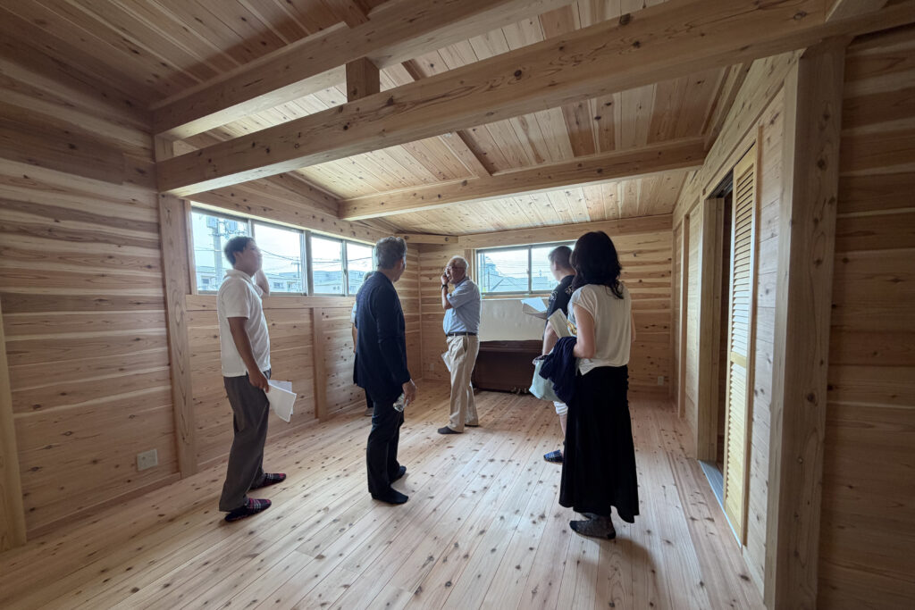 板倉造りの住宅の完成見学会の様子。杉無垢材あらわしの部屋で和やかに談笑している。